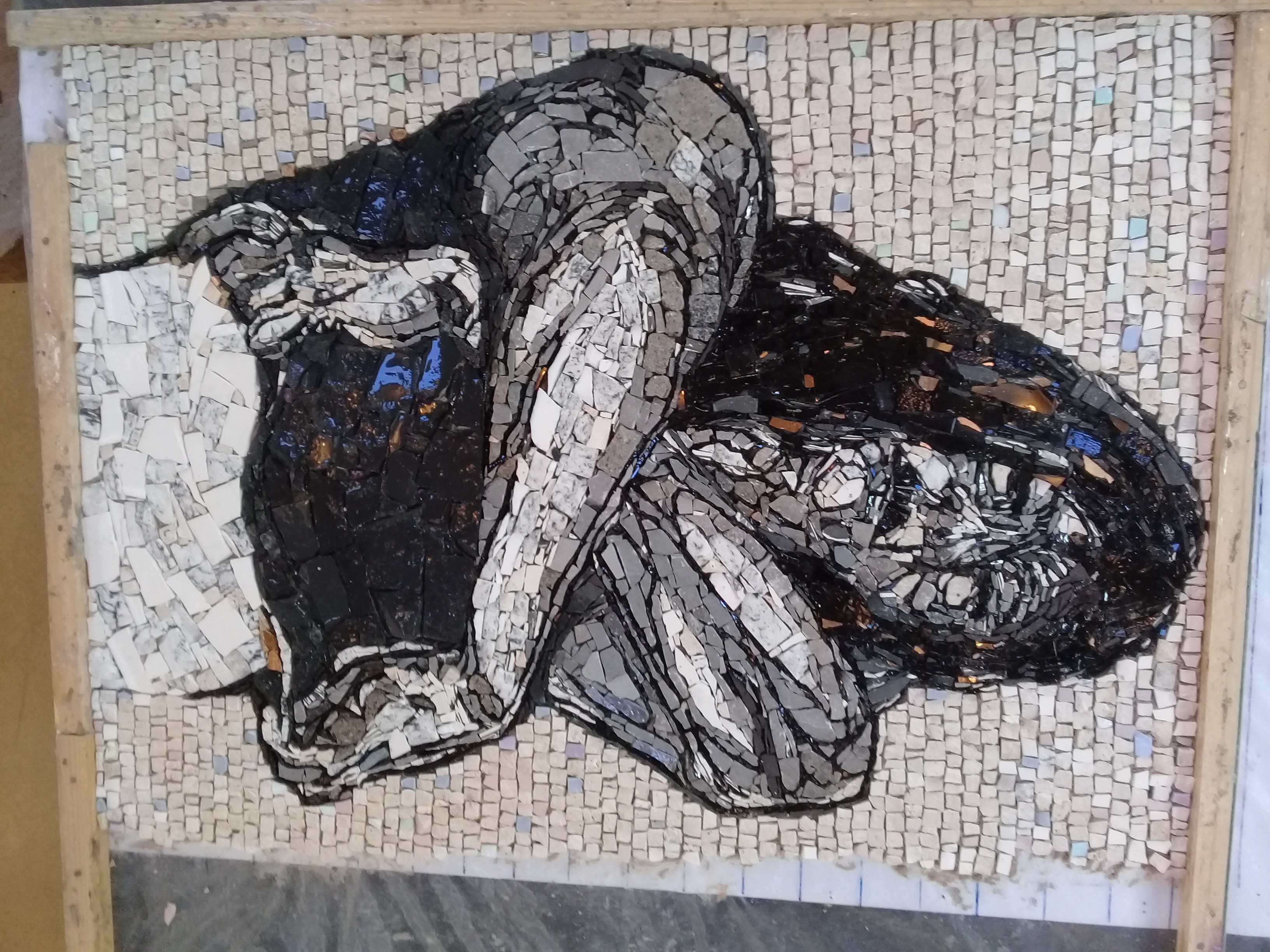A finished mosaic portrait artwork in black, white and gold tile