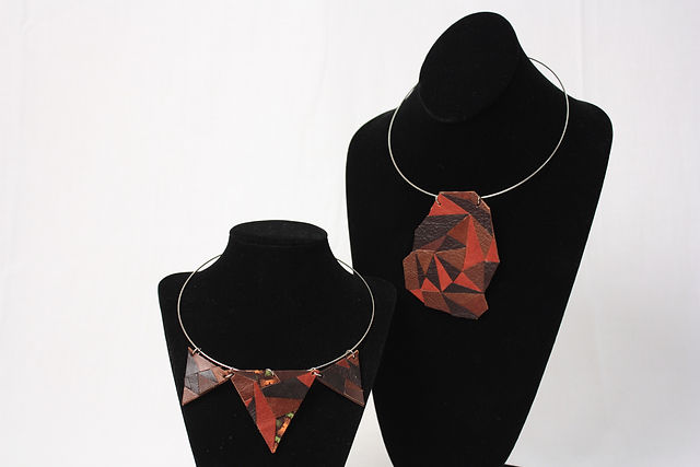 Two leather necklaces, a faceted pendant and a triangle bib, displayed on black mannequin busts