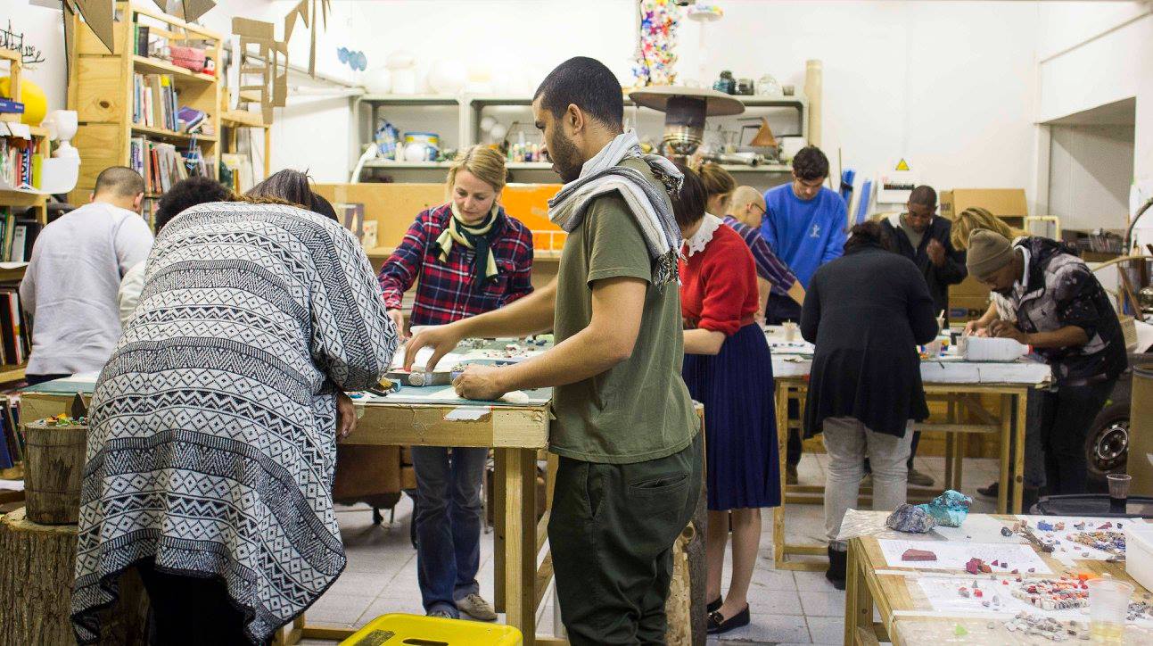 A full studio workshop session — many visitors working side by side at long tables